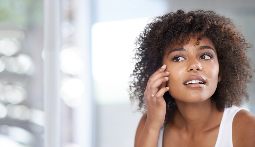 A woman touching the right side of her face under the eye area.